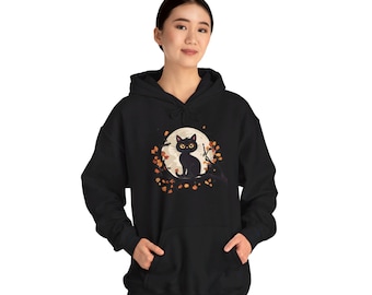 Puede incluir: Sudadera negra con un gato negro sentado en una rama frente a una luna llena. El gato tiene ojos amarillos y la luna tiene un brillo amarillo. La rama está rodeada de hojas naranjas.
