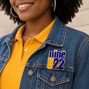 May include: A gold-toned metal pin featuring the text 'one' in yellow, 'nine' in blue, and the number '22' in blue with a white outline. Below the number 22, the Greek letters Sigma Gamma Rho are displayed in white on a blue background.