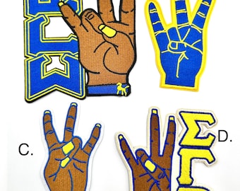 May include: Four embroidered patches with a hand gesture and letters. The patches are yellow, blue, and brown. The letters on the patches are "AKW", "ΣFP", and "D".