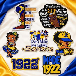May include: A collection of seven embroidered patches featuring blue and gold themes. Designs include a woman in a headwrap, a word cloud with Sigma Gamma Rho symbols, a cartoon character, a group of women, a woman in a cap, and the year 1922.