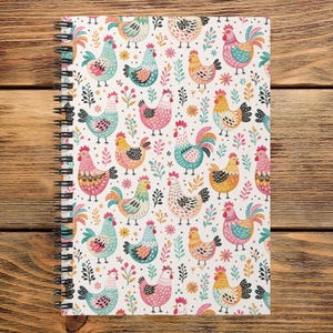 May include: A spiral-bound notebook featuring a repeating pattern of colorful chickens in shades of pink, blue, yellow, and orange, interspersed with small floral and leaf motifs on a white background, with a black metal wire coil on the left side.