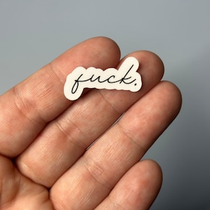 May include: White sticker with the word "fuck." written in black cursive.
