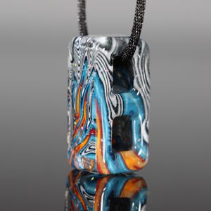 May include: A rectangular pendant with a black cord. The pendant features a colorful, swirled design with shades of blue, orange, and white. The design is encased in a clear, glossy material, creating a unique and eye-catching accessory.