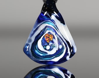May include: A handcrafted glass pendant with a swirling blue, white, and teal design. The pendant features a small, orange heart-shaped accent in the center and hangs from a black cord. The glass has a glossy finish.