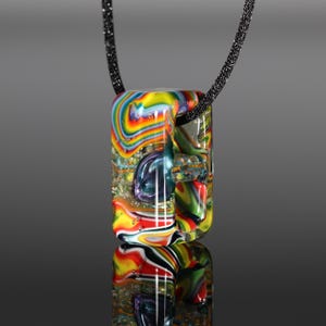 May include: A colorful glass pendant with a rainbow swirl design. The pendant is rectangular with rounded edges and is suspended from a black cord. The glass features vibrant hues of yellow, red, blue, and green.