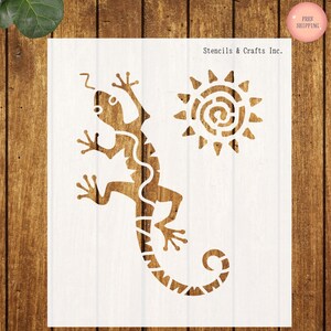 May include: A stencil featuring a lizard and sun design. The lizard is brown with a white pattern, and the sun has a spiral center. The text "Stencils & Crafts Inc." is visible. The stencil is on a white background.