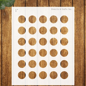May include: A white stencil with 30 evenly spaced, 1-inch diameter circles. The circles have a wood grain appearance. The text "Stencils & Crafts Inc." is printed at the top right. The stencil is on a wooden surface.