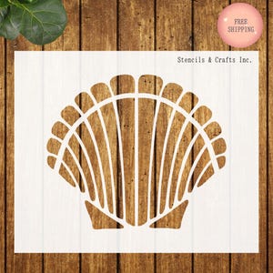 May include: A white seashell stencil with a detailed design, set against a wooden background. The stencil features a scallop shell shape, perfect for crafting and DIY projects. The text "Stencils & Crafts Inc." is visible.