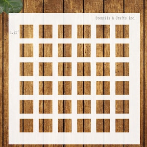 May include: A white stencil with a grid pattern of squares, each measuring 1.25 inches. The stencil is labeled "Stencils & Crafts Inc." in black text. The background is a wooden surface.