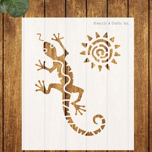 May include: A white stencil featuring a stylized lizard with a curled tail and a sun with a spiral design. The stencil is labeled "Stencils & Crafts Inc."
