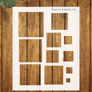 May include: White stencil with various square and rectangular cutouts. The stencil is labeled "Stencils & Crafts Inc." and is placed on a wooden surface. The design includes a large rectangular shape divided into smaller squares and rectangles.