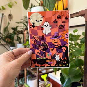 May include: A Halloween-themed sticker with a purple, orange, and black color scheme. It features a witch's cauldron, a ghost, pumpkins, and the text "I put a spell on you".