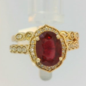 May include: A gold ring with a large oval ruby gemstone surrounded by smaller diamonds. The ring is set in a delicate filigree design.
