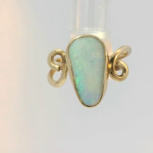 May include: A gold ring with a teardrop-shaped opal gemstone. The ring has a delicate, twisted design.