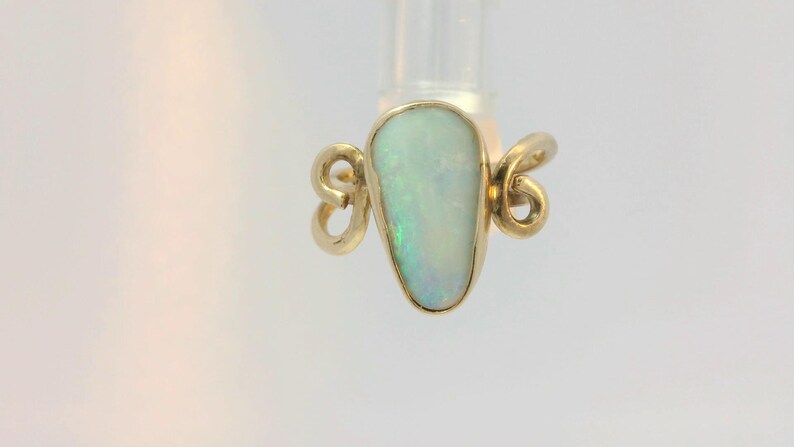 May include: A gold ring with a teardrop-shaped opal gemstone. The ring has a delicate, twisted design.