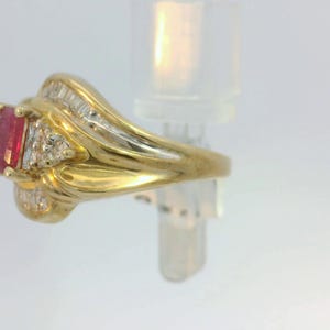 May include: A gold ring with a red gemstone and small diamonds set in the band.
