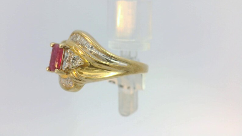 May include: A gold ring with a red gemstone and small diamonds set in the band.