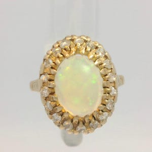 Peut inclure: Une bague en or avec une grande opale ovale entour&eacute;e de diamants plus petits.