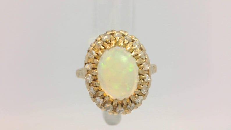 Peut inclure: Une bague en or avec une grande opale ovale entour&eacute;e de diamants plus petits.