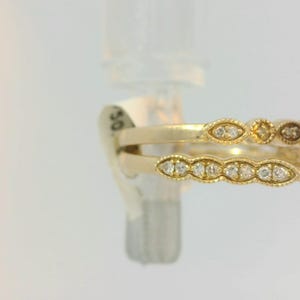 May include: A gold ring with a large red gemstone surrounded by smaller diamonds. The ring is set on a white background.