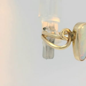 May include: A gold ring with a white opal stone set in a bezel setting. The ring has a unique, twisted band.