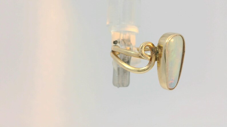 May include: A gold ring with a white opal stone set in a bezel setting. The ring has a unique, twisted band.