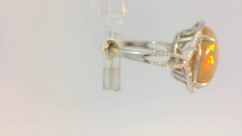 May include: A silver ring with a large, oval-shaped opal gemstone set in a delicate, diamond-encrusted setting.
