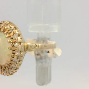 Peut inclure: Une bague en or avec une grande opale ovale entour&eacute;e d'un halo de petits diamants.
