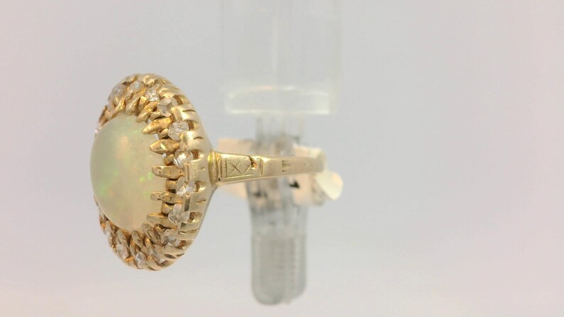 Peut inclure: Une bague en or avec une grande opale ovale entour&eacute;e d'un halo de petits diamants.