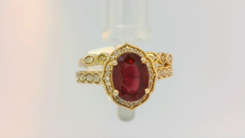 May include: A gold ring with a large oval ruby gemstone surrounded by smaller diamonds. The ring is set in a delicate filigree design.