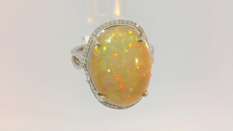 May include: A silver ring with a large oval opal gemstone surrounded by a halo of small diamonds.