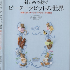 Könnte beinhalten: Ein Buchcover mit blauem Hintergrund und Illustrationen von gestickten Figuren aus den Peter Rabbit Geschichten. Der Titel des Buches lautet "The World of Peter Rabbit" und der Untertitel lautet "Stitch and Thread: The World of Peter Rabbit".