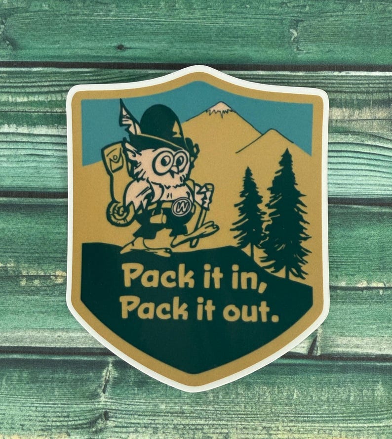 May include: A shield-shaped sticker featuring an owl hiker with a backpack, hat, and walking stick. The owl is set against a backdrop of mountains and pine trees. The text "Pack it in, Pack it out" is displayed in a bold font.