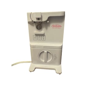 Pode incluir: Um abridor de latas elétrico ajustável branco da Sunbeam. O aparelho possui um grande mostrador, um cabo de alimentação e um mecanismo de corte. O logotipo da Sunbeam é visível em vermelho. O abridor de latas foi projetado para ficar em uma bancada.