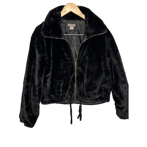 May include: A black faux fur jacket with a zip-up front and a drawstring hem. The jacket has a wide collar and long sleeves. The jacket is hanging on a wooden hanger.