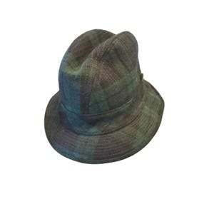 May include: A green and navy plaid bucket hat. The hat features a rounded crown and a short brim. The plaid pattern is a classic design, and the hat appears to be made of a soft, woven fabric. A stylish accessory.