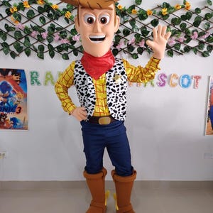Könnte beinhalten: Ein Ganzkörper-Woody-Kostüm mit braunem Cowboyhut, gelbem Hemd mit schwarz-weißem Kuhfell-Print, blauer Hose und braunen Stiefeln. Das Kostüm beinhaltet ein rotes Halstuch und eine große lächelnde Gesichtsmaske.