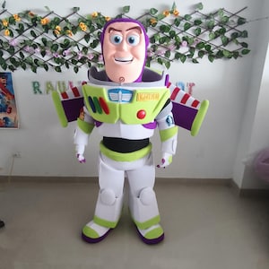 Könnte beinhalten: Ein Ganzkörper-Buzz Lightyear-Kostüm mit lila Kopf, weiß-grünem Raumanzug und Flügeln. Das Kostüm hat eine hellgrüne Brustplatte mit dem Wort "LIGHTYEAR" und lila Akzenten. Die Figur steht vor einer dekorativen Wand.