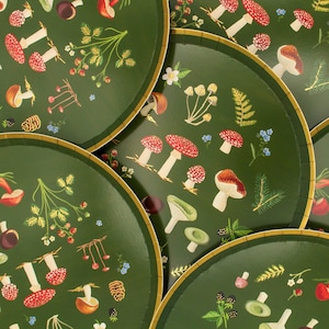 May include: Set of four green paper plates with a mushroom and forest design. The plates feature illustrations of mushrooms, leaves, and berries.