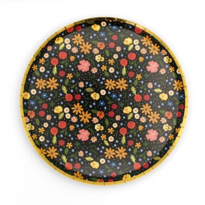 May include: A black paper plate with a gold rim features a floral pattern with red, yellow, orange, and pink flowers on a black background.