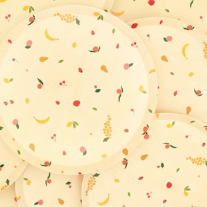 May include: A set of four yellow paper plates with a repeating pattern of fruit and berries. The plates are stacked on top of each other.