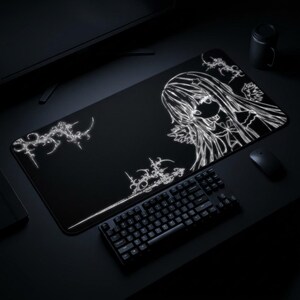May include: Black rectangular mousepad with a white anime-style illustration of a girl with long hair and decorative floral elements. A black keyboard and mouse are in the foreground.