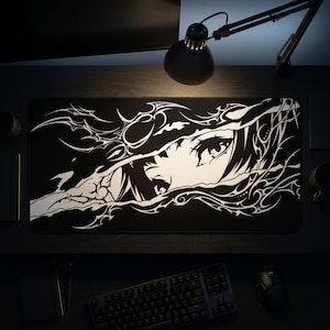 May include: A rectangular desk mat featuring a high-contrast black and white graphic design. The artwork displays a stylized anime-style eye peering through a jagged, torn-paper effect surrounded by intricate, flowing tribal-inspired line patterns.