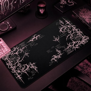 Può includere: Un tappetino da scrivania rettangolare nero con un motivo grafico rosa ripetuto di linee affilate, spinose, a forma di stella e forme astratte. Il design è concentrato lungo i bordi e gli angoli, lasciando il centro per lo più nero.