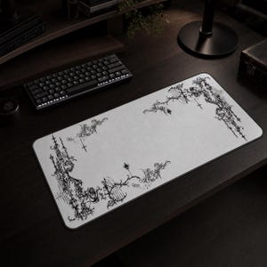 May include: A rectangular desk mat featuring a light gray surface with intricate black line art illustrations of ornate gates, ironwork, and decorative flourishes concentrated along the corners and edges of the mat, creating a framed effect.