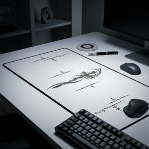 Może przedstawiać: Biała podkładka pod biurko z czarną obwódką i czarnym abstrakcyjnym wzorem. Na biurku znajduje się czarna klawiatura, dwie myszy komputerowe, długopis i podstawka. Wzór na podkładce to seria czarnych linii i kształtów.