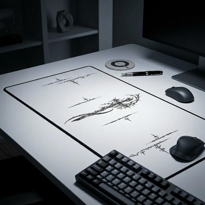 May include: A white desk mat with a black border and a black abstract design. A black keyboard, two computer mice, a pen, and a coaster are on the desk. The design on the mat is a series of black lines and shapes.