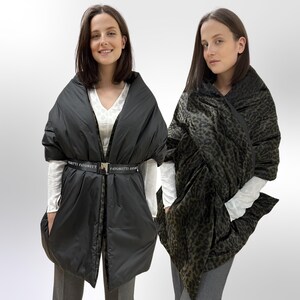 May include: Two women wearing black and green puffer scarves with a leopard print. The black scarf has a black belt with the text "FAVORITTI FAVORITTI" printed on it.