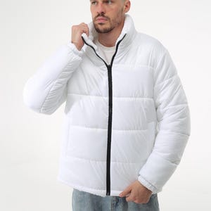 May include: A white puffer jacket with a black zipper and a high collar. The jacket has a quilted design and is made of a lightweight material.