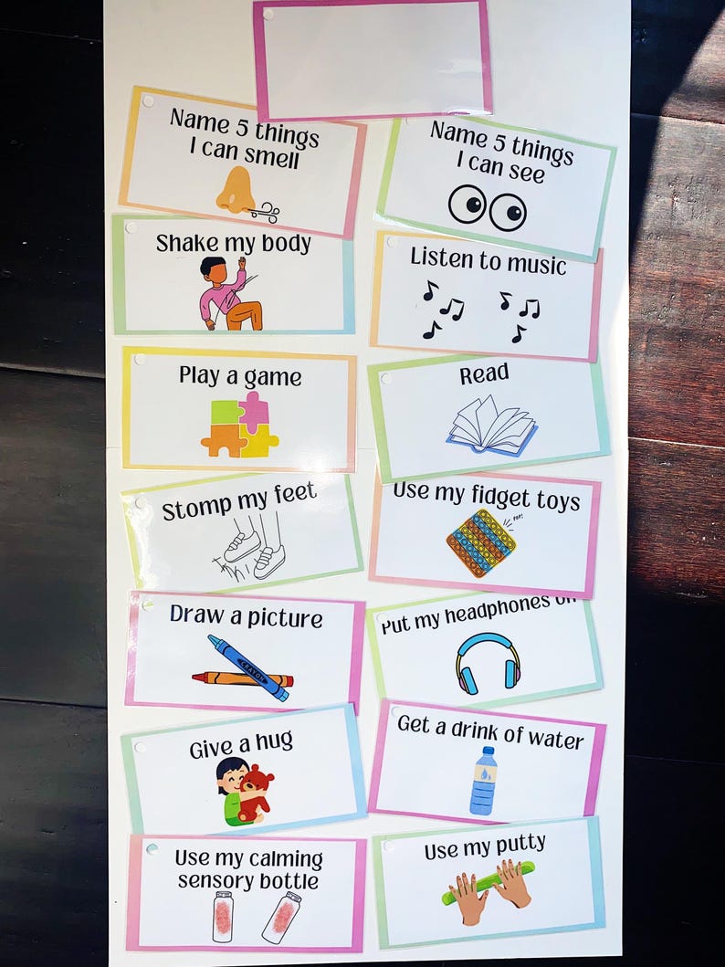 May include: A colourful chart with 12 different calming activities for children. The activities include: name 5 things I can smell, shake my body, play a game, stomp my feet, draw a picture, give a hug, use my calming sensory bottle, name 5 things I can see, listen to music, read, use my fidget toys, put my headphones on, get a drink of water, and use my putty.